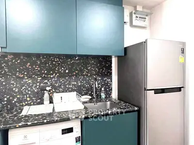 Modern kitchen with sleek cabinets, terrazzo countertop, and stainless steel fridge.