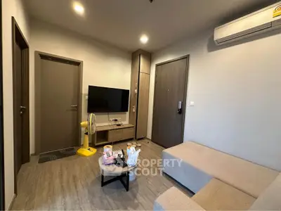 Modern living room with cozy beige sofa, wall-mounted TV, and sleek wooden flooring.