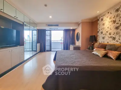 Spacious bedroom with balcony and city view, modern decor and ample natural light.