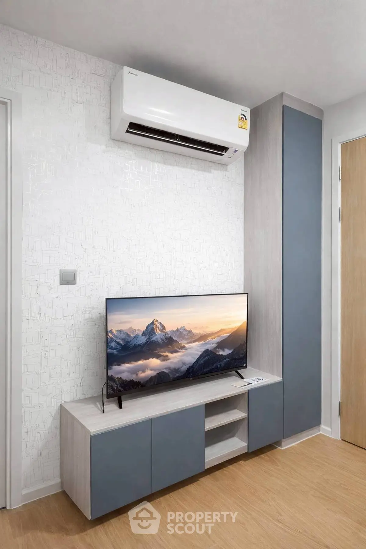 Modern living room with sleek TV unit and air conditioning, featuring stylish cabinetry and wood flooring.