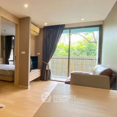 Modern living room with large window and garden view, featuring cozy seating and natural light.
