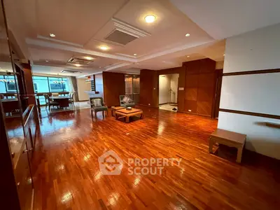 Spacious living room with wooden flooring and modern lighting, ideal for family gatherings.