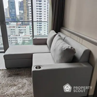 Modern living room with stylish gray sofa and city view from large window.