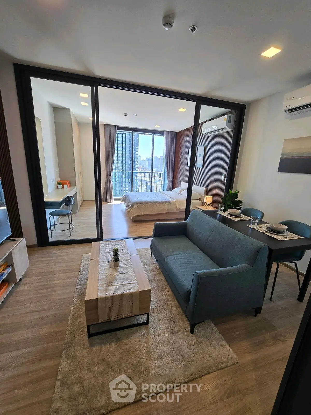 Modern open-plan living room with stylish furniture and city view from bedroom