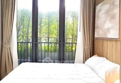 Bright bedroom with large window and garden view, featuring elegant curtains and modern decor.