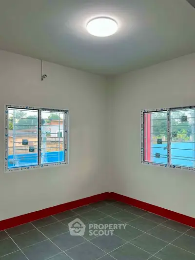 Bright room with large windows and modern tile flooring, perfect for a cozy living space.