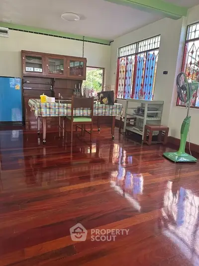 Charming kitchen with polished wooden floors and colorful decor, featuring a dining table and vintage appliances.