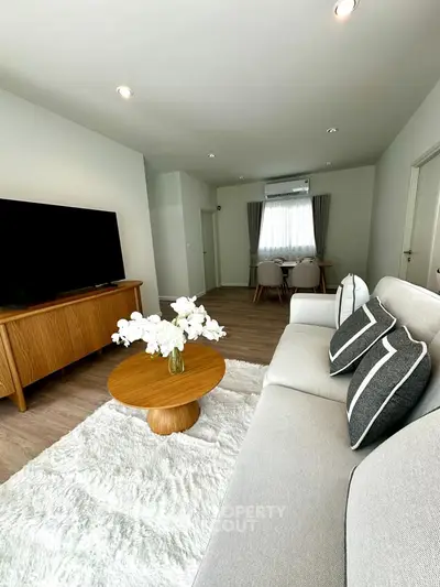 Modern living room with stylish decor and cozy ambiance, featuring a plush rug and elegant furniture.