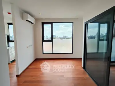 Spacious modern apartment with wooden floors and large windows offering city views.