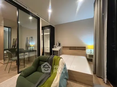 Modern bedroom with stylish decor, featuring a cozy green armchair and sleek mirrored wardrobe.