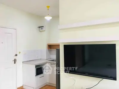 Modern compact kitchen with microwave and flat-screen TV in cozy apartment.