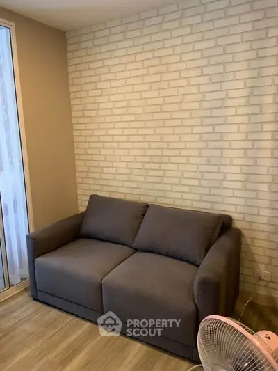 Cozy living room with modern sofa and stylish brick accent wall.