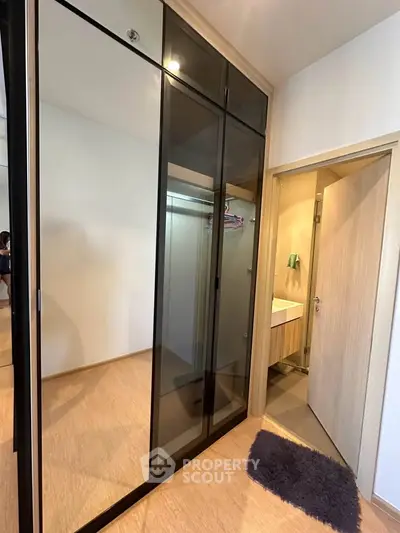 Modern bedroom with sleek glass wardrobe and ensuite bathroom