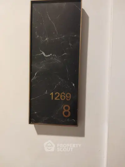 Elegant apartment number plaque with marble design and gold numbers.