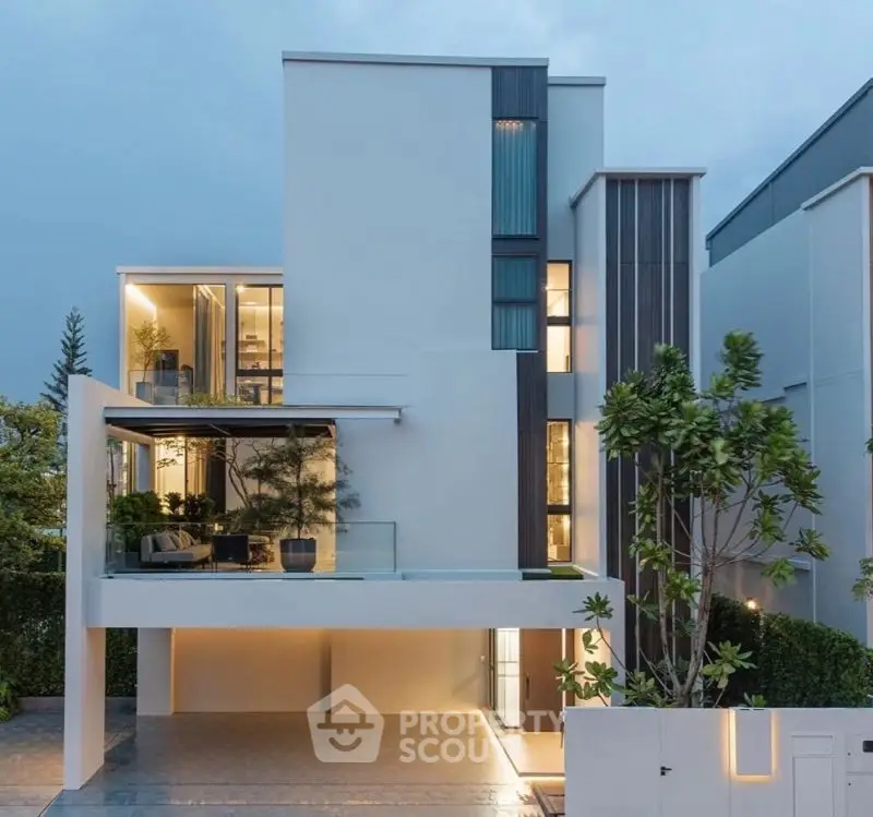 Modern luxury home with sleek architecture and large windows, showcasing contemporary design and lush greenery.