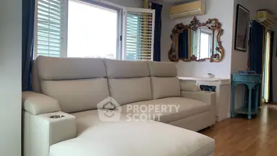 Elegant living room with plush sofa and vintage mirror, featuring air conditioning and wooden flooring.