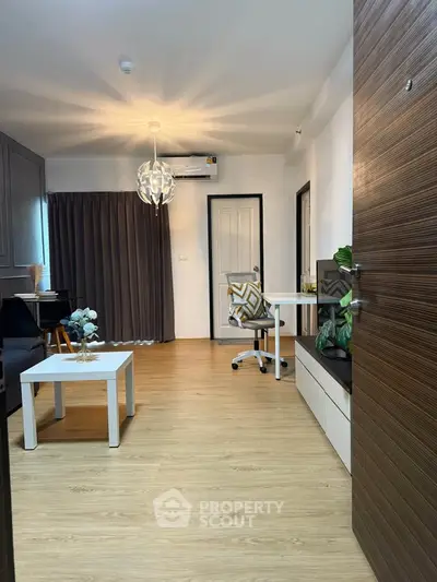 Modern living room with stylish decor and wooden flooring, featuring a cozy seating area and workspace.