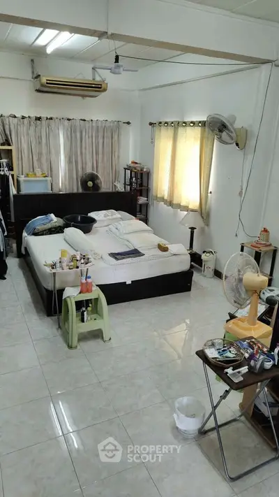 Spacious bedroom with double bed, air conditioning, and natural light from large windows.