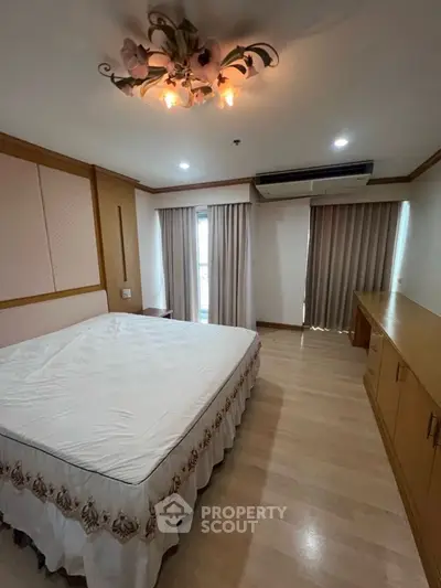 Spacious bedroom with elegant lighting and large windows in modern apartment.