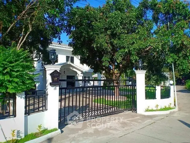 Elegant white villa with gated entrance and lush greenery in a serene neighborhood.