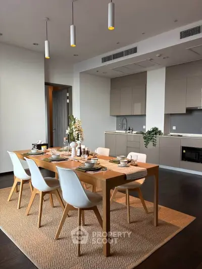 Modern dining area with sleek kitchen, wooden table, and elegant decor in a stylish apartment.