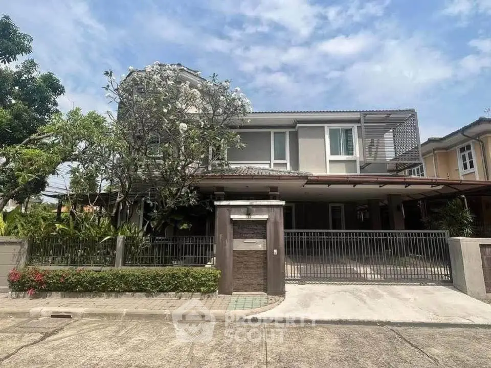 Modern two-story house with lush garden and gated entrance in a serene neighborhood.
