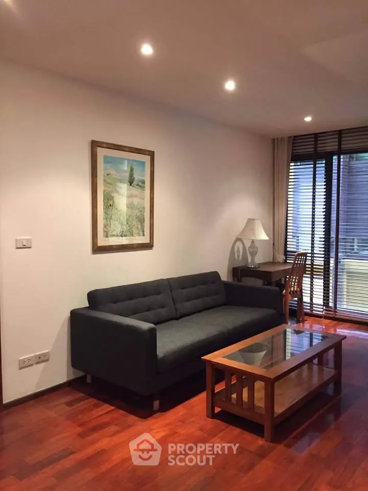 Elegant living room with modern sofa, wooden flooring, and natural light from large windows.