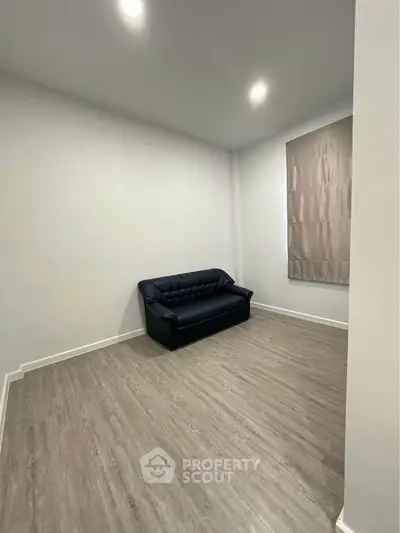 Minimalist living room with sleek black sofa and modern flooring