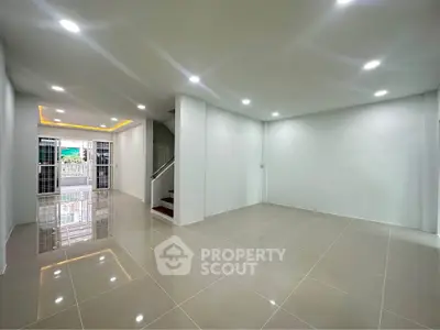 Spacious modern living room with glossy tiled floors and bright recessed lighting.