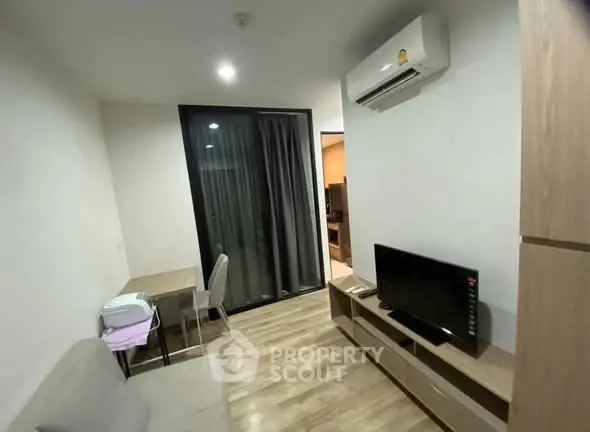 Modern living room with air conditioning and TV, featuring a cozy workspace and sleek wooden flooring.