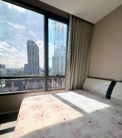 Modern bedroom with large window offering stunning city view in high-rise apartment.