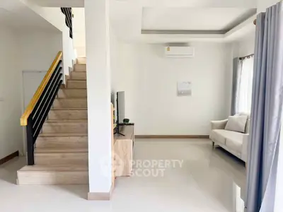 Modern living room with staircase, sleek sofa, and air conditioning unit.