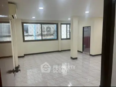 Spacious empty room with tiled flooring and large windows in a modern apartment.