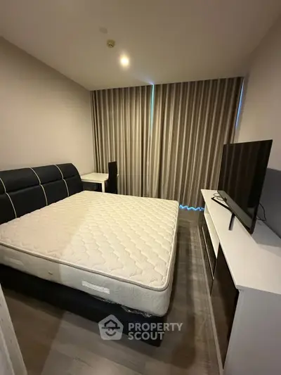 Modern bedroom with sleek furniture and large window, perfect for urban living.