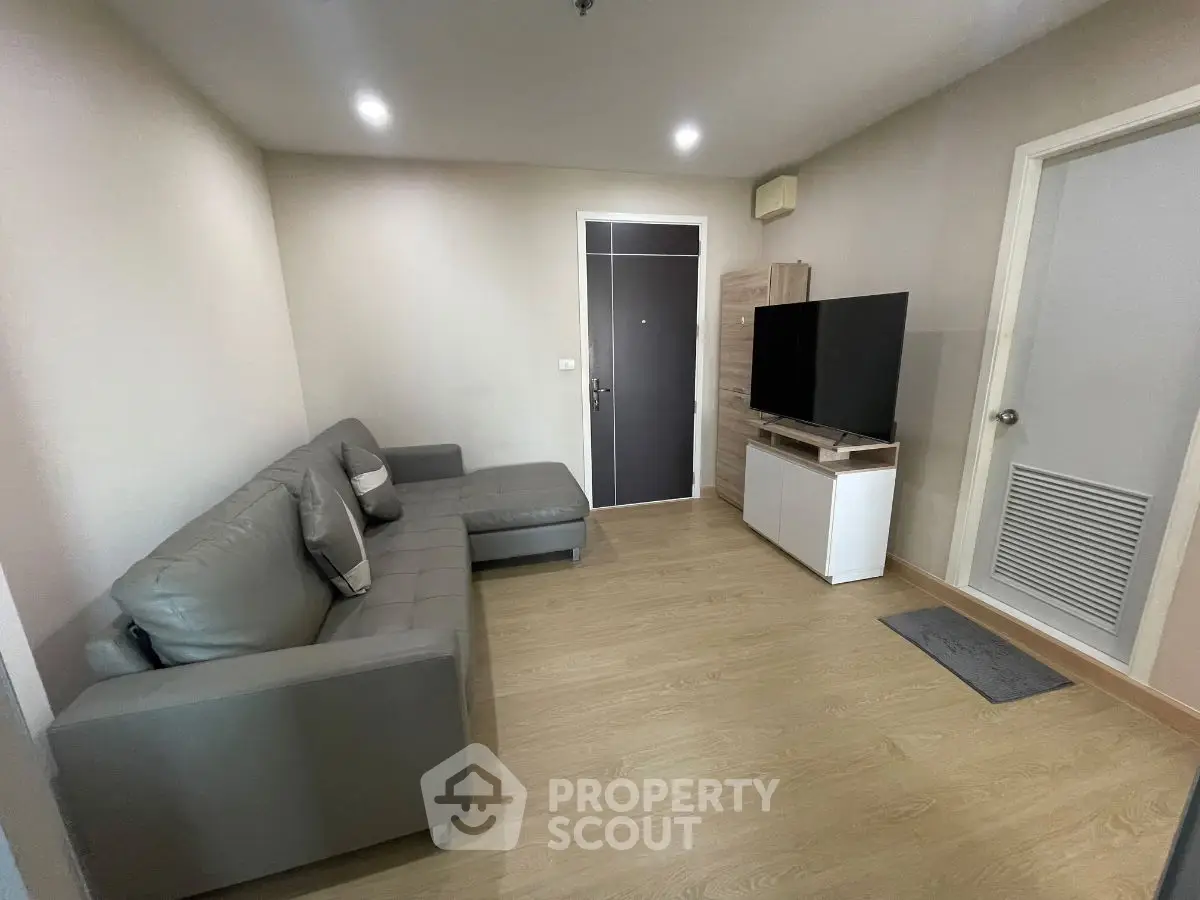 Modern living room with sleek gray sofa and large TV, perfect for relaxation and entertainment.