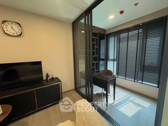 Modern living room with adjacent study area featuring glass partition and stylish decor.