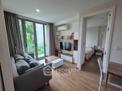 Modern living room with cozy sofa and TV unit, adjacent to a bright bedroom with garden view.