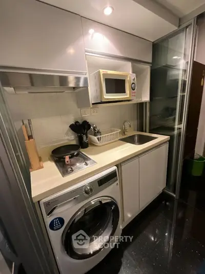 Compact modern kitchen with washing machine and microwave in sleek apartment