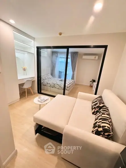 Modern studio apartment with cozy living area and bedroom separated by glass partition.