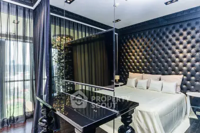 Luxurious bedroom with tufted wall and modern decor, featuring a sleek TV setup.