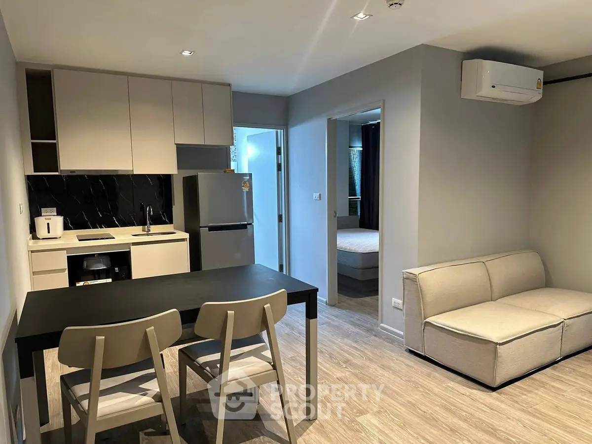 Modern open-plan kitchen and living area with sleek furniture and neutral tones.