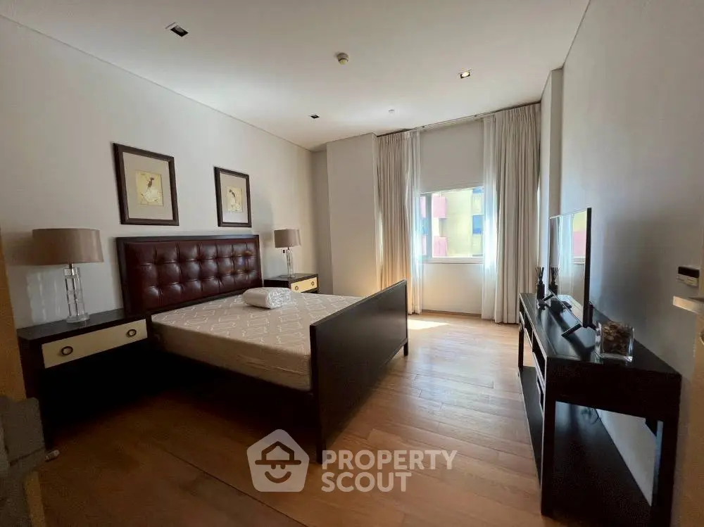 Spacious bedroom with modern decor and large window for natural light.