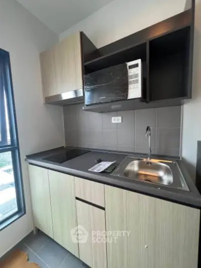 Modern compact kitchen with microwave and sleek cabinetry in a bright apartment