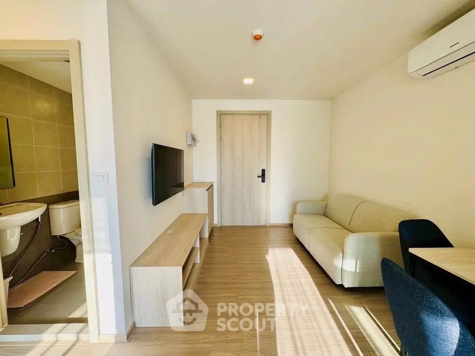 Modern living room with cozy sofa, wall-mounted TV, and wooden flooring