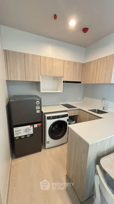 Modern kitchen with sleek cabinetry, washing machine, and refrigerator in a compact layout.
