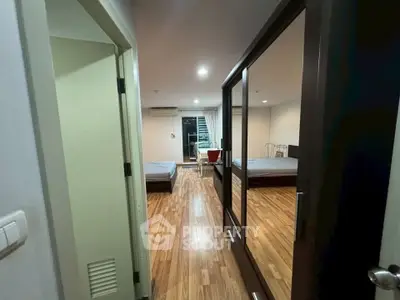 Spacious bedroom with wooden flooring and mirrored closet doors in modern apartment.
