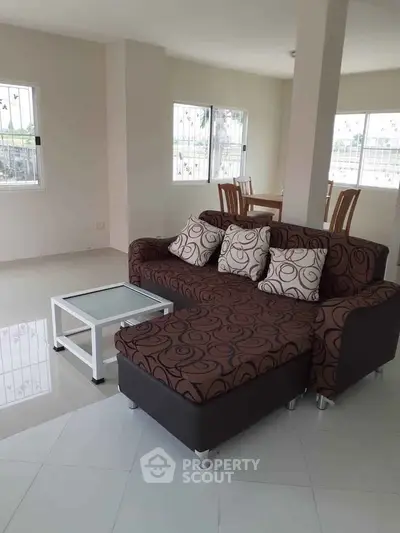 Spacious living room with modern sofa and dining area, bright natural light, perfect for family gatherings.