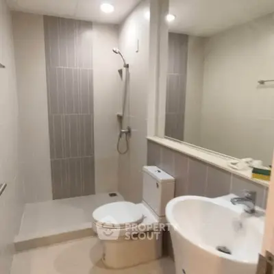 Modern bathroom with shower, toilet, and sink in sleek design.