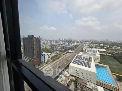 Stunning cityscape view from high-rise window overlooking highway and modern buildings.