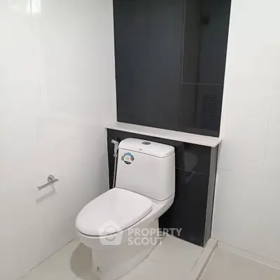 Modern bathroom with sleek white tiles and contemporary toilet design.